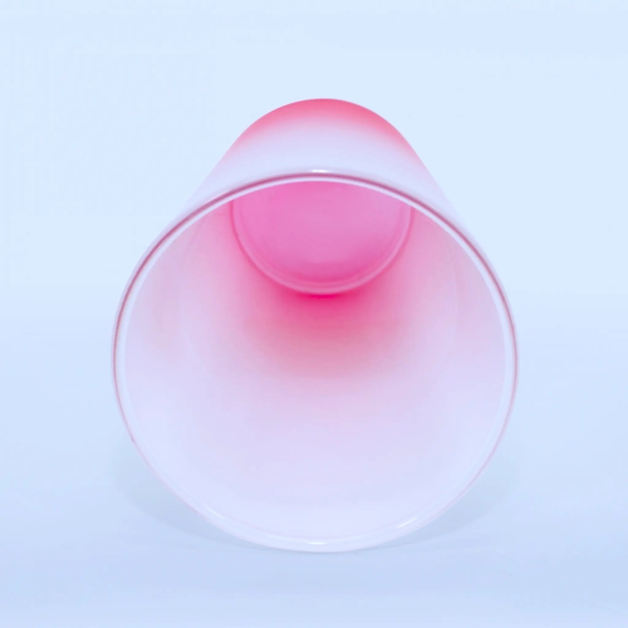 Interior del vaso de vidrio rojo empavonado con forma cónica.